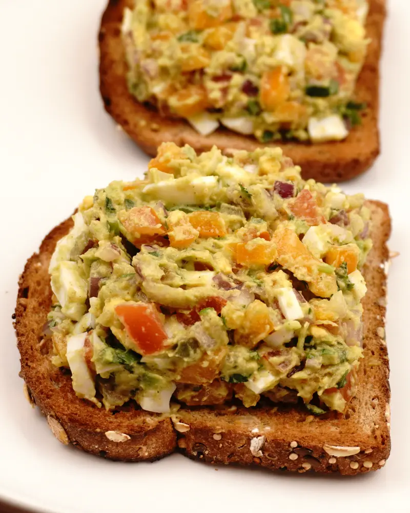 Avocado Egg Veggie Salad Open Sandwich - close up view of finished dish plated and garnished