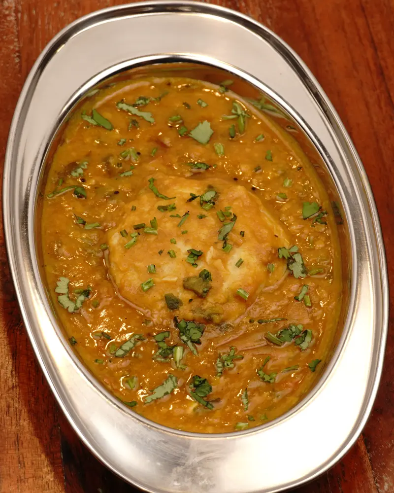 Restaurant Style Vegetable Sambar - close up view of finished dish plated and garnished