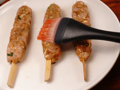 Prepare liquid ghee, just before placing them on hot pan, use pastry brush to apply ghee on top surface of the chicken skewers   