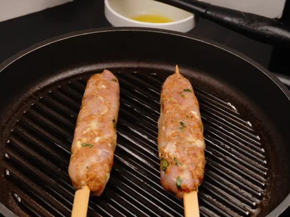 Place the oiled surface chicken skewers on the hot grill pan and continue to cook them without moving, untill to attain dark brown grill marks underside the chicken skewers for about 4 to 5 minutes over medium flame 
