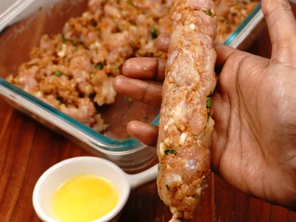Apply oil on your hands, take one portion of chicken mixture, make a cylindrical shape, use two hands to form long cylindrical shape around the skewer