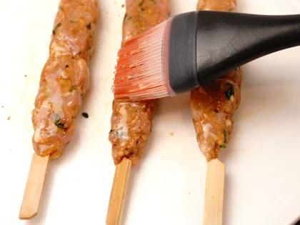 Just before placing them on hot pan, use pastry brush to apply oil on top surface of the chicken skewers   